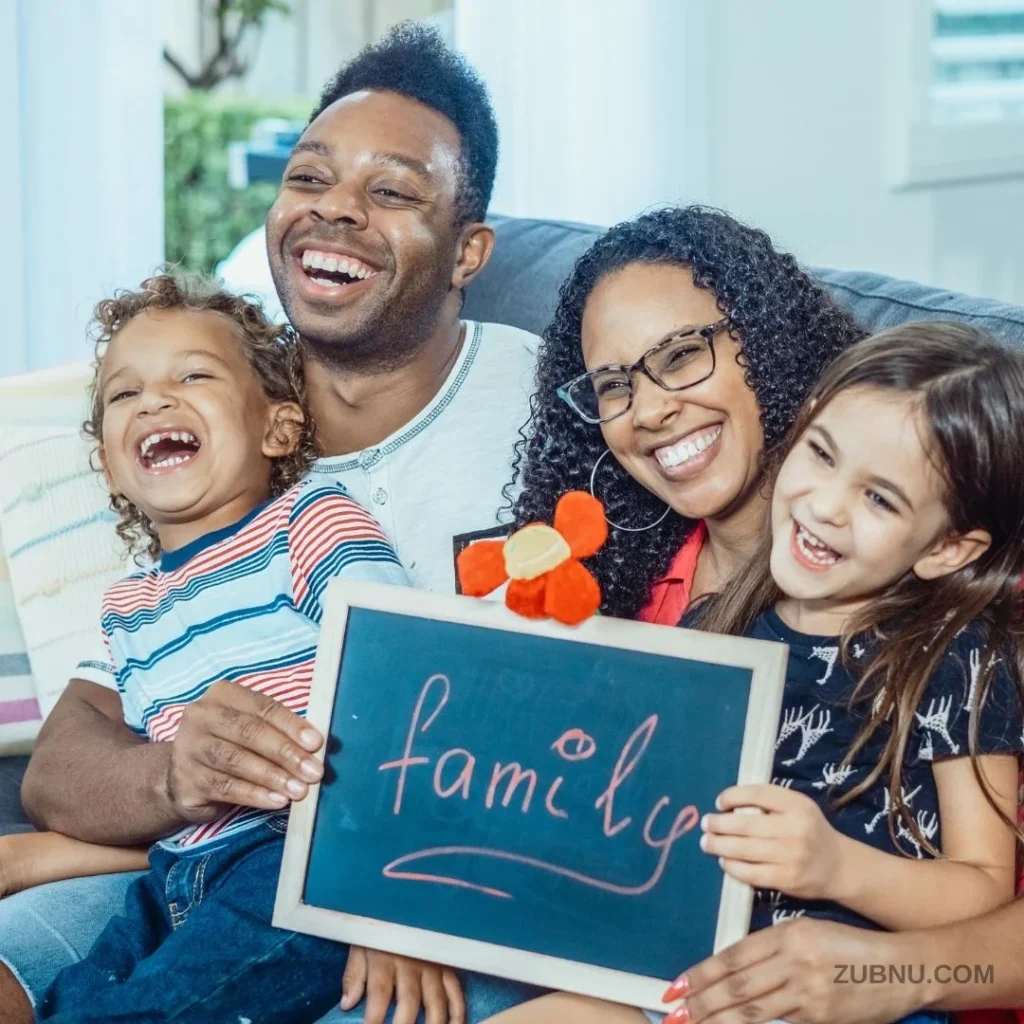 A happy family with two children sitting on a sofa with their parents holding a slate that reads FAMILY.jpg