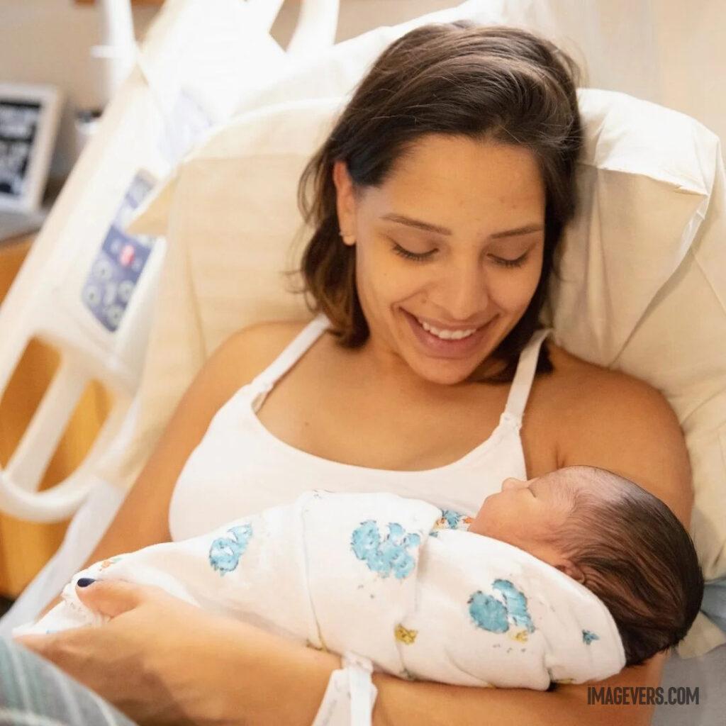 A newborn baby is sleeping on his mothers lap in the hospital wearing a white cloth and his mother is happy to see him.jpg 6 11zon