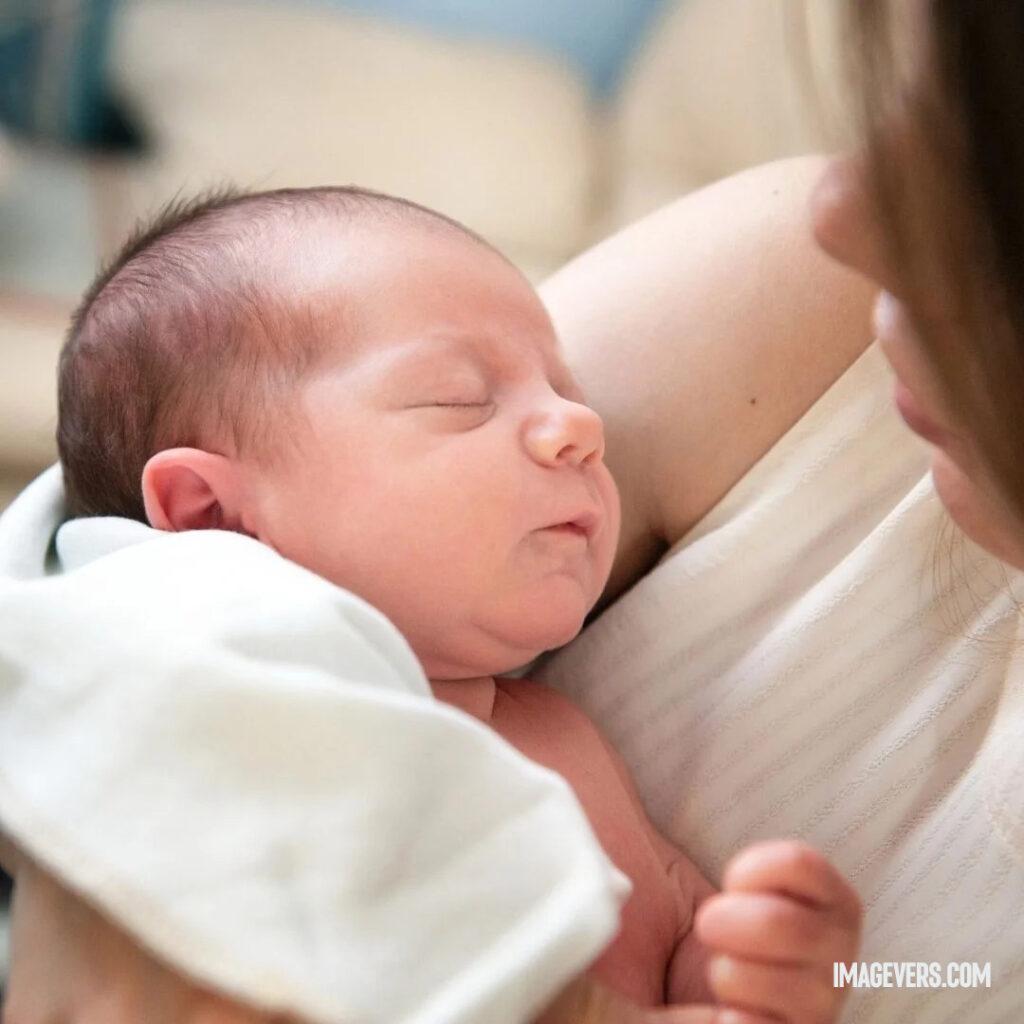 A newborn baby is sleeping peacefully on his mothers lap as his mother gazes at him as he sleeps.jpg 9 11zon
