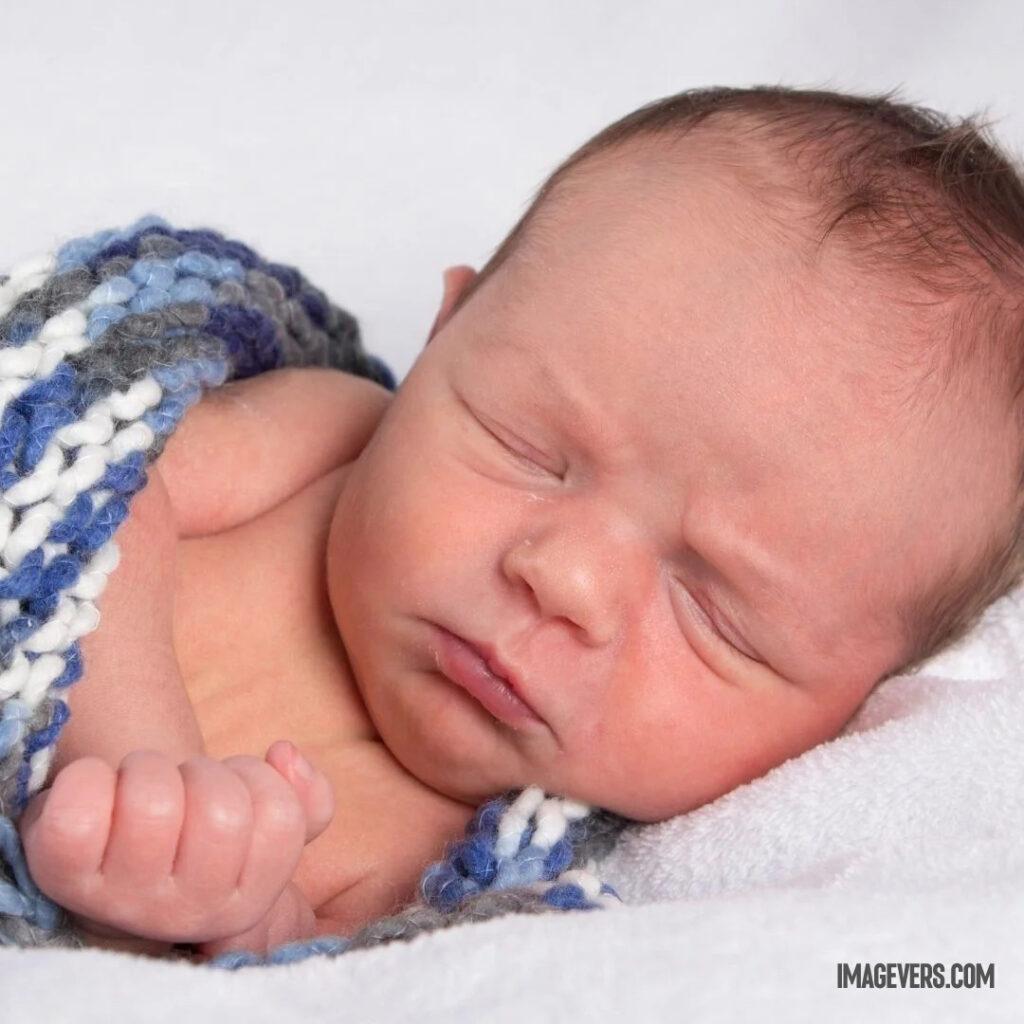 A newborn baby is wrapped in a blue gray white woolen cloth on a white velvet blanket and is sleeping on its left side.jpg 18 11zon