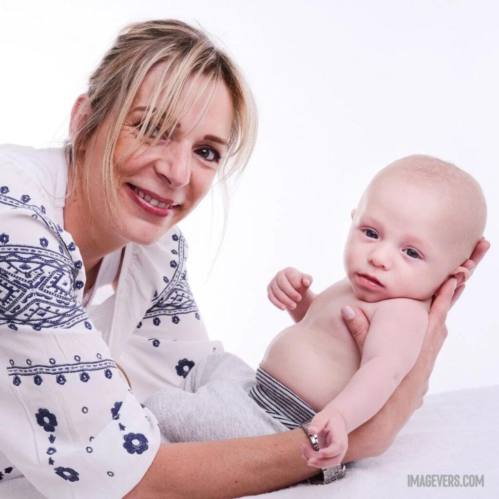 A newborn baby on a white bed in his mothers arms Wearing black and white pants Both the baby and the mother are looking at someone.jpg 20 11zon