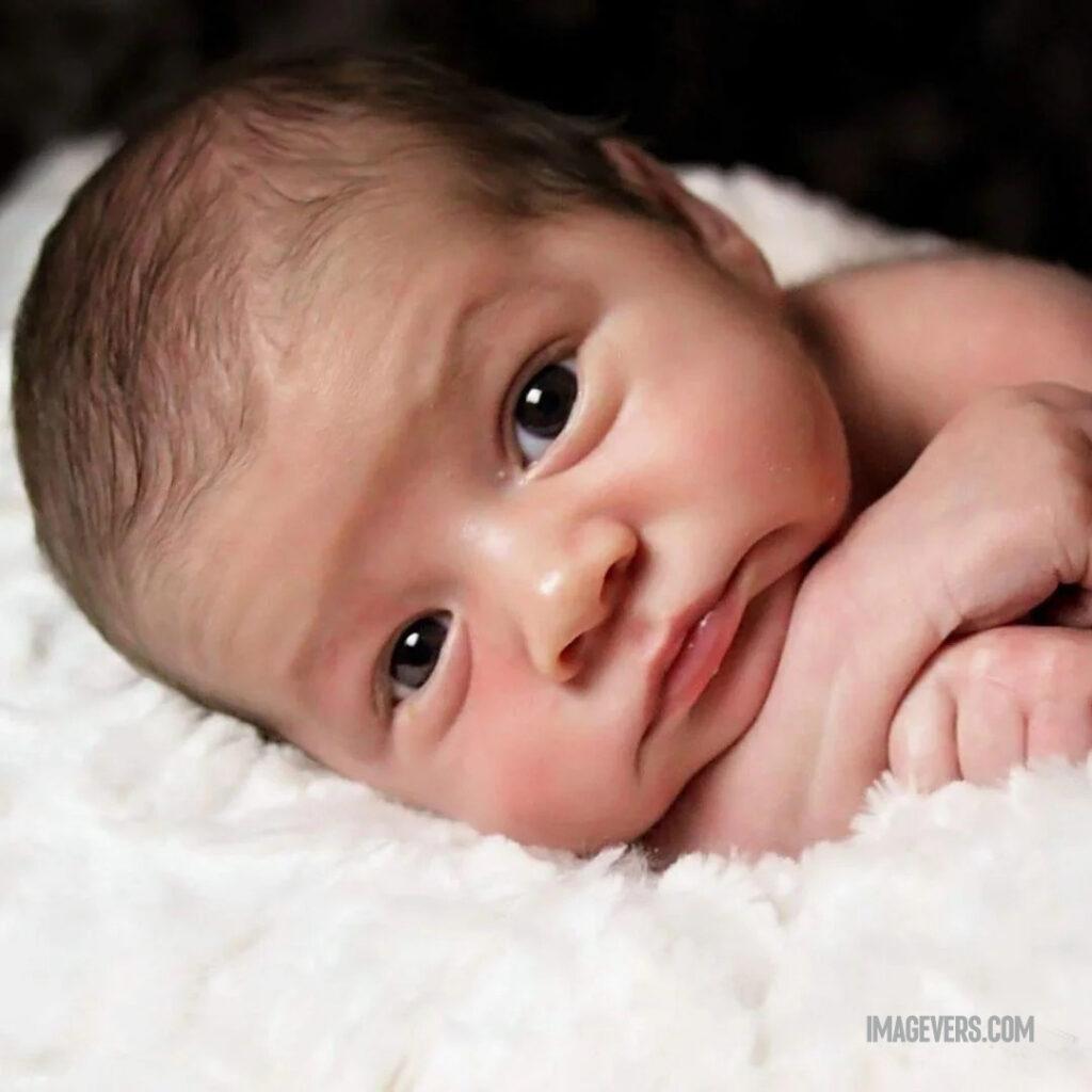 A newborn baby sleeping on a white blanket and looking lovingly.jpg 21 11zon