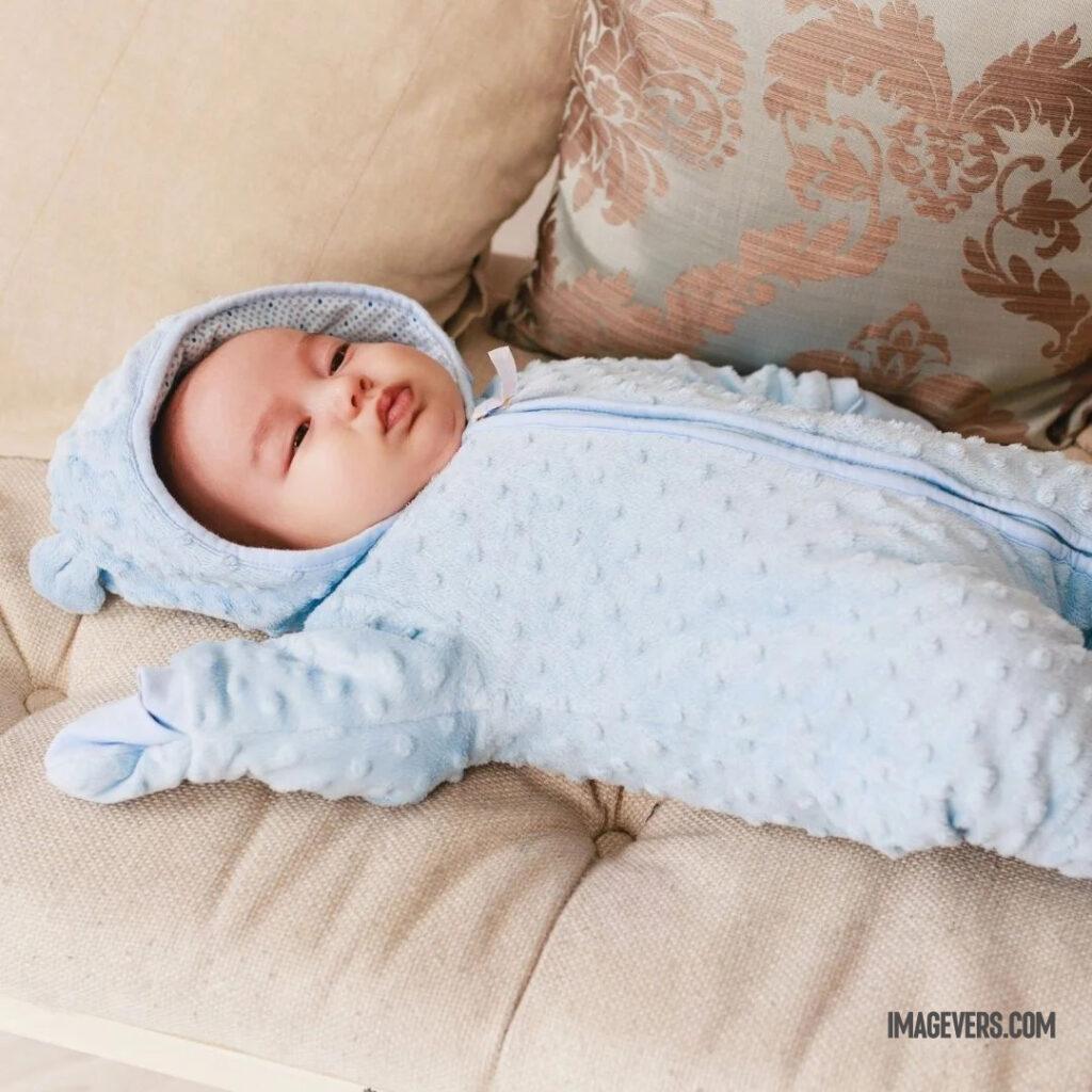A newborn baby wearing a blue fleece and hat is looking up on a padded couch.jpg 22 11zon