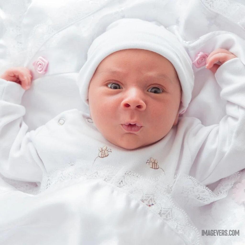 A newborn baby wearing a white woolen cloth and a cap is looking up in wonder on a white bed.jpg 30 11zon